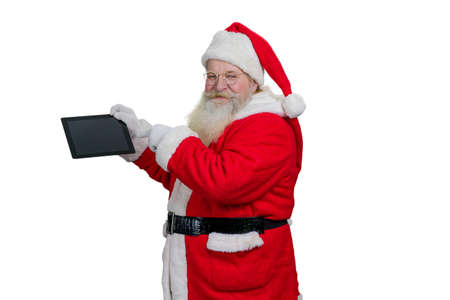 Santa Claus with computer tablet. Senior Santa Claus holding digital computer tablet and pointing on blank touch screen with index finger, white background.の写真素材