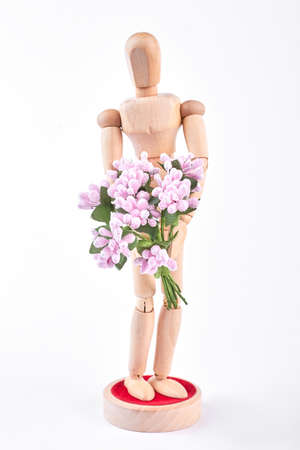 Wooden dummy holding pink flowers. Wooden human mannequin with artificial bouquet isolated on white backgrond. Gift and greeting concept.の写真素材