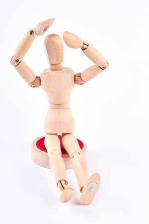 Wooden dummy raised hands above head. Human wooden mannequin with raised hand near head sitting over white background. Wooden mannequin in desperation.の写真素材