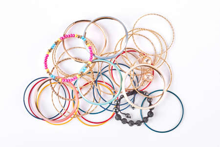 Stack of different wrist bands for women, white background. Female bangles on sale.