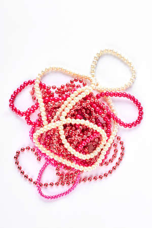 Pile of colorful beads necklace. Red, pink and white beads necklace over white background. Woman fashion classic neck accessories.の写真素材