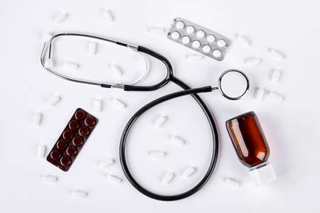 Stethoscope, pills, brown medical bottle. Medical equipment on white background, top view.の写真素材