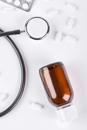 Glass bottle, black stethoscope, pills. Medical instruments on white background, top view. Medicine and health care concept.の写真素材