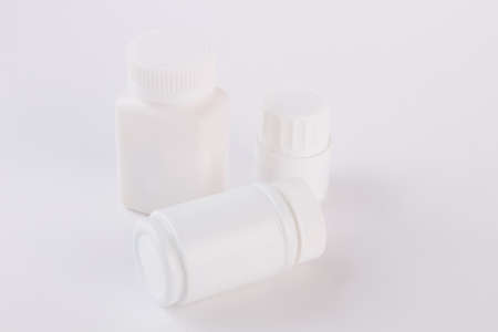 Different sizes white bottles for pills. Blank small, big and medium sizes plastic packaging bottles with cap for cosmetics or vitamins.の写真素材