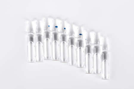 Raw of break-seal medical ampoules. Set of glass ampoules with medicine liquid for injections, white background.の写真素材