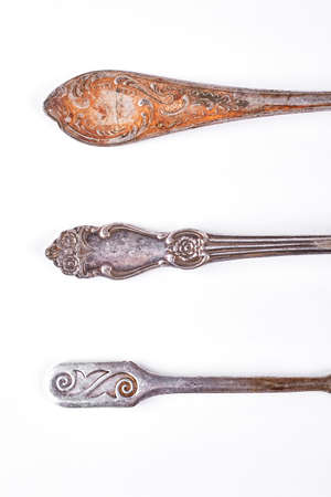 Rusty spoons and forks, top view. Antique kitchen tableware isolated on white background, cropped image. Ancient vintage kitchen utensils.の写真素材