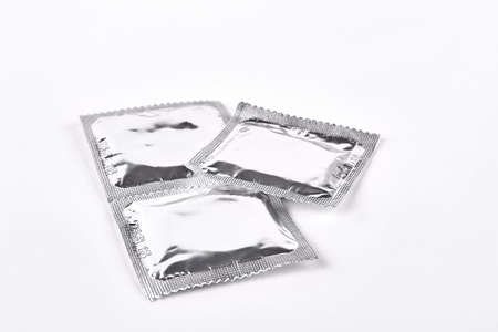 Condoms in silver package. Three contraceptives wrapped in silver packages. Latex protection against aids and infections.の写真素材