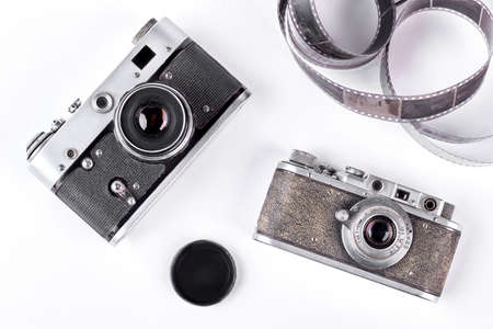 Old-fashioned cameras, film tape, cap. Two vintage film cameras on white background.の写真素材