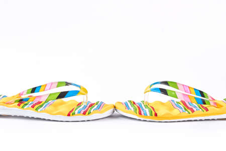 Yellow slippers with multicolored stripes on white background. Summer vacation concept.