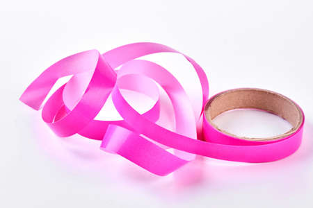 Pink tape for gift packaging. Roll of beautiful pink ribbon isolated on white background.の写真素材