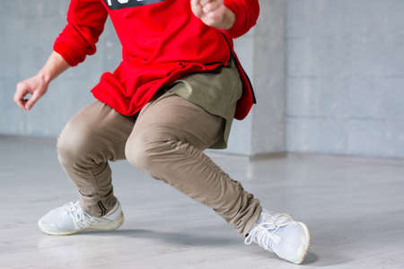 Stylish male hip-hop dancer in action. Trendy guy dancing break dance on grey background. Street style dancing.の写真素材