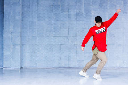 Young handsome break dancer in action. Stylish caucasian rap dancer dancing on grey studio background. Skill, energy and rhythm concept.の写真素材