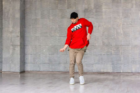 Young rapper dance on grey background. Young street style dancer posing on studio background.の写真素材