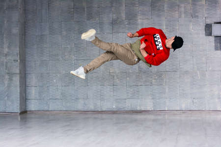 Young dancer in jumping. Modern style rap dancer in high jumping on grey background.の写真素材