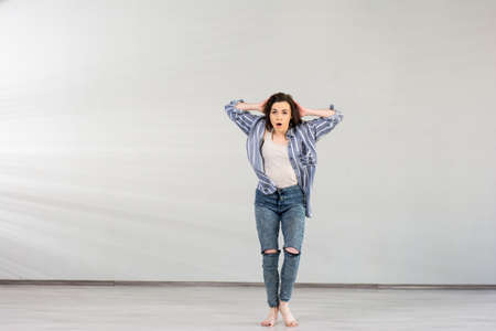 Young pretty dancer posing in studio. Young energetic girl holding hands behind her head performing contentemporary dance.の写真素材