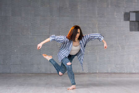 Modern dance performance by young girl. Young beautiful dancer posing on studio background.の写真素材