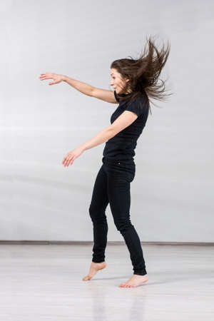 Slim girl in dance movement. Young beautiful modern style dancer posing on a studio background.の写真素材