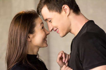 Couple of lovers close to each other. Happy smiling loving couple hugging on studio background....