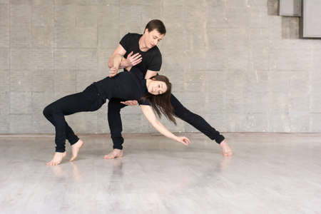 Beautiful couple dancing social dance. Young skillful dancers performing modern dance on grey studio background.の写真素材