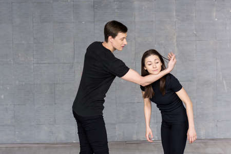 Young dancers practicing in studio. Young girl holding her head on boy hand, practicing dance element. Young skillful dancers in action.の写真素材