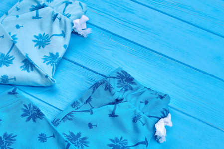 Close up of casual cotton baby clothing. Toddler baby natural spring or summer leggings in detail, blue wooden background.の写真素材