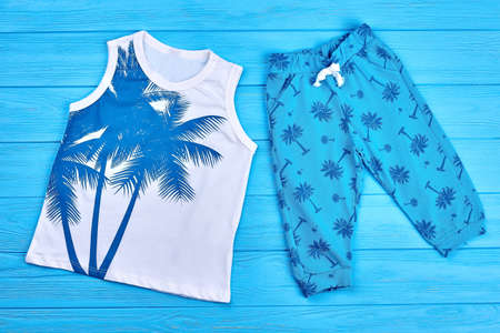 Set of cute childrens summer clothing. Fashion style summer suit for infant baby on blue wooden background. Toddlers summer outfit.の写真素材