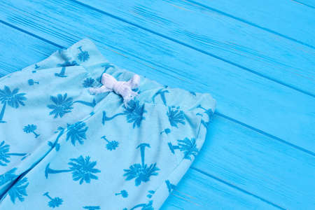 Close up of trendy capri for kids. Detail of modern unisex children pants, blue wooden background. Natural childs clothing.の写真素材
