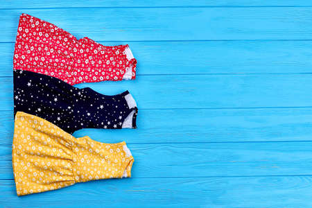 Set of baby-girl summer dresses. New folded vintage little girl dresses, copy space. Top view of colorful baby-girls sundresses.の写真素材