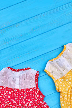 Casual baby dress and copy space. Vintage design little girls summer dresses on blue wooden background. Colored summer baby apparel.の写真素材