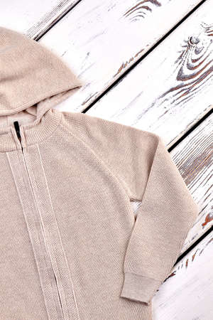 Kids beige knitted hooded jacket. Cotton knitted hooded pullover for childrens, vintage wooden...