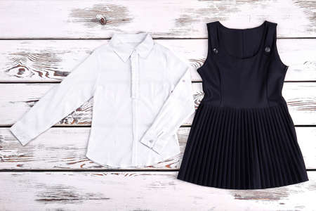 Girl white shirt-frill and dress for school. Girls black traditional school dress and white blouse, old wooden background. Girls school uniform.の写真素材