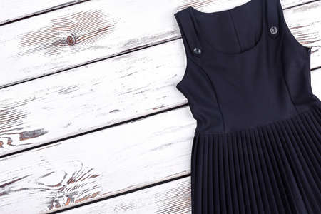 Girls black school dress, copy space. Girls school uniform sleeveless pleated dress on white wooden background, top view. Kids school uniform on sale.の写真素材
