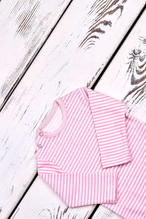 Newborn girl cute striped bodysuit. Infant girl long sleeve organic romper on white wooden background, top view.の写真素材