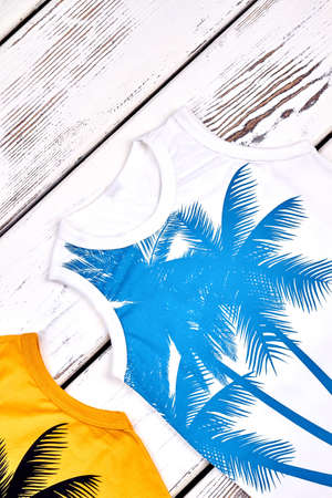 Little girl trendy sleeveless t-shirt. Kids modern print tops on wooden background, top view. Childs organic t-shirt on sale.の写真素材