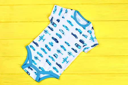 Infant boy high quality bodysuit. Baby boy new summer romper on yellow wooden background. Infants summer outfit.の写真素材