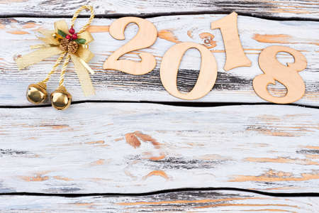 Merry Christmas and happy New Year 2018. Wooden digit 2018 decorated with golden bell, copy space for text, vintage wooden background. Happy New Year concept.の写真素材