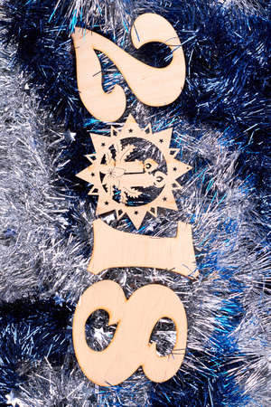New Year number 2018 from wood. Wooden digit 2018, symbol of New Year on blue and silver tinsel...