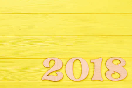 Wooden number 2018 on colored background. Number 2018 on yellow wooden background and copy space. Digit 2018 and space for greeting.の写真素材