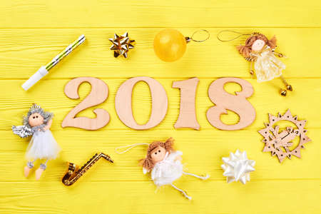 Wooden number 2018 and Christmas ornaments. Wooden numbers forming the number 2018 for the new year 2018 with angels, bows on a yellow wooden background. Christmas 2018 background.の写真素材