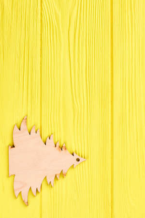 Decorative wooden Christmas tree. Cut out wooden silhouette of sruce on yellow wooden background and copy space. New Year and Christmas concept.の写真素材