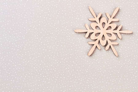 Wooden snowflake on winter paper background. Cut out wooden decorative snowflake on grey background with white dots and copy space. New Year concept.の写真素材