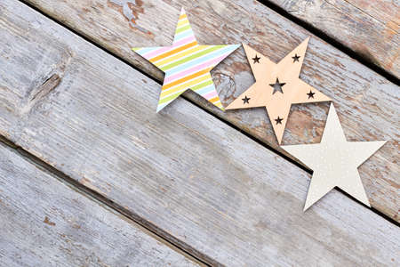 Paper and wooden handmade stars. Handmade Christmas stars ornaments on rustic wooden background and copy space.の写真素材