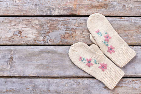 Pair of female hand mittens on wooden background. Woman white woolen knitted gloves on old wooden background, copy space.の写真素材