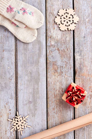 New Year and Christmas wooden background. Cut out wooden snowflakes, handmade gift box, craft paper, knitted mittens on old wooden background, copy space.の写真素材