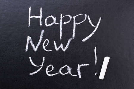 Inscription Happy New Year on black board. Black board with hand inscription Happy New Year with...