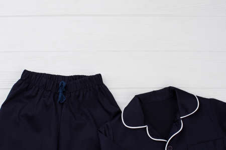 Dark blue pajama set on white wooden background. Pants and shirt. Casual sleepwear for kids.の写真素材