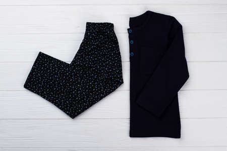 Black pajama set on white wooden background. Long sleeve t-shirt, loose-fitting pants with floral print. Sleepwear for girls.の写真素材