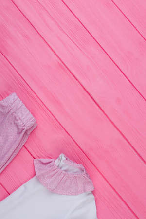 Kids clothes on wooden table. Pink and white girls pajama set. Sale, new arrival. Free place for your text.の写真素材