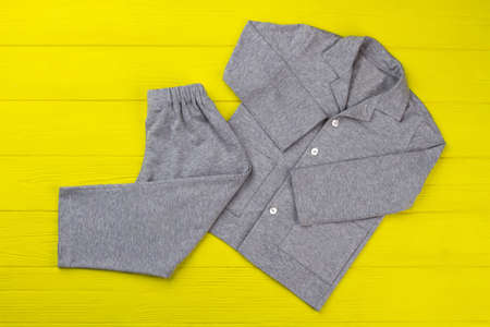 Boys pajama set on yellow table. Simple design and gray melange fabric. Comfy pants and shirt for good sleep.の写真素材