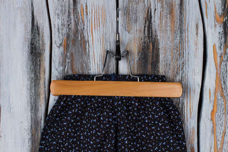 Black pants on wooden hanger. Garment with girlish floral pattern. Girls clothing apparel for lounging at home.の写真素材